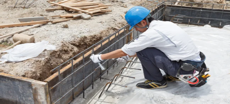 Operário trabalhando na recuperação de armadura oxidada em um canteiro de obras